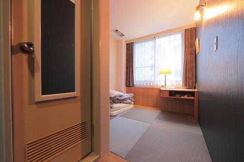 a room with a door and a window and a bed at Hotel Sun Garden Matsuyama in Matsuyama