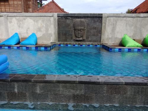 a swimming pool with a statue in the middle at Devadav Hostel (Bunk Bed) Nusa Lembongan in Nusa Lembongan