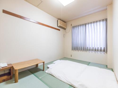 a small room with a bed and a table at Hotel Isesaki East in Isesaki