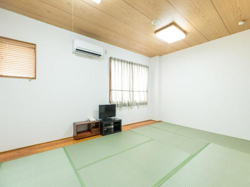 un salon vide avec une télévision et un plafond dans l'établissement Hotel Isesaki East, à Isesaki