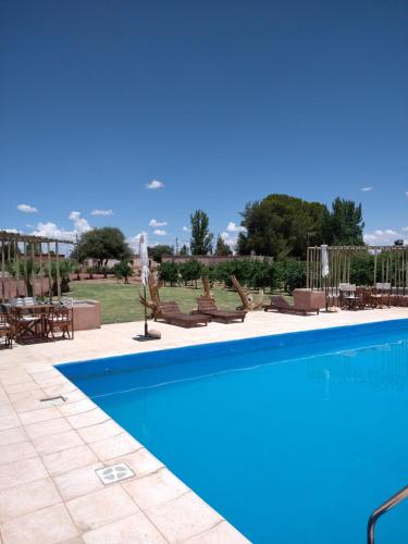 Una gran piscina con sillas y una mesa. en Hotel Cañon de Talampaya, en Villa Unión