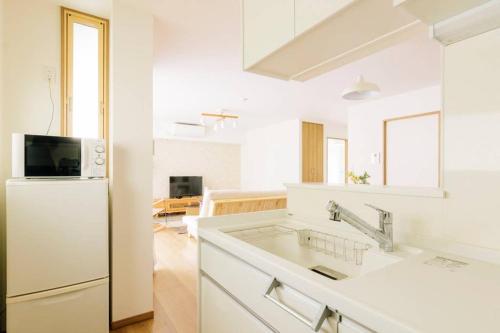a white kitchen with a refrigerator and a sink at Akiba Residence in Tokyo