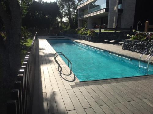 a swimming pool in front of a house at DEPTO PARQUE PINARES FRENTE AL LAGO, PRIMERA LINEA, NUEVO in Pucón