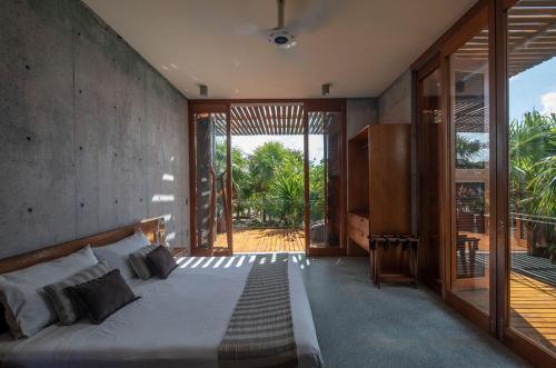 1 dormitorio con 1 cama y puerta corredera de cristal en Beachfront Villa in the middle of jungle!, en Tulum