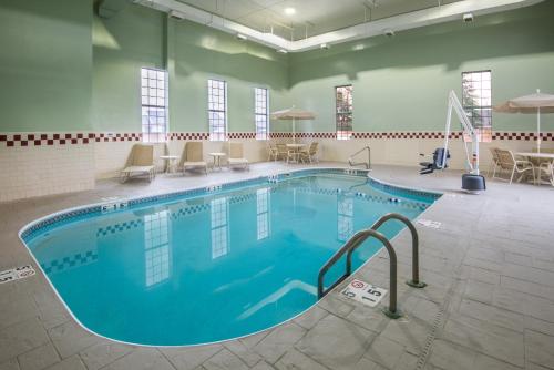 a pool in a large room with chairs and tables at Holiday Inn Express Cleveland Airport - Brook Park by IHG in Brook Park