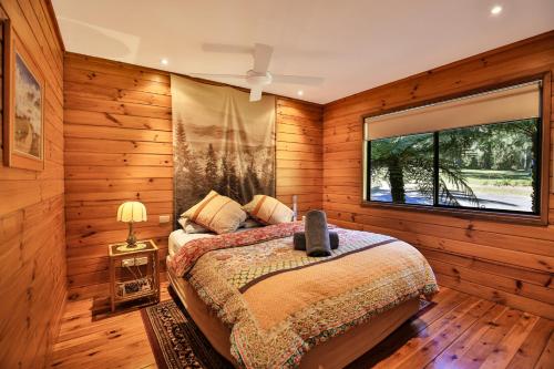 a bedroom with a bed and a large window at Siver Cabin in Kangaroo Valley