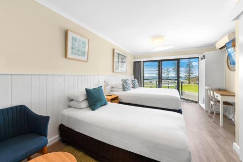 a hotel room with two beds and a chair at ibis Styles Port Macquarie in Port Macquarie