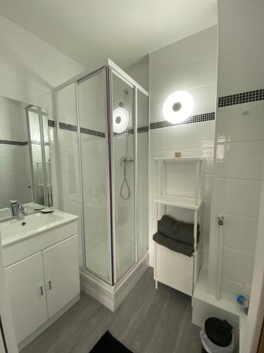 une salle de bain blanche avec une douche et un lavabo dans l'établissement La digue 45 Rue des Lais de Mer, à Benerville-sur-Mer