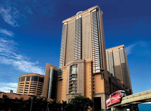 een groot hoog gebouw met een trein ervoor bij KL Cozy Suite Times Square in Kuala Lumpur