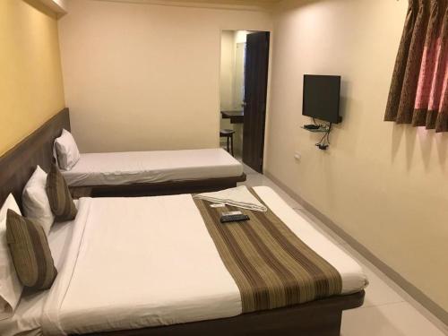 een hotelkamer met 2 bedden en een televisie bij Lucky Service Apartments in Mumbai