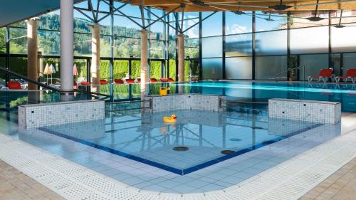 a swimming pool in a building with glass walls at Bruggerhof - Camping, Restaurant, Hotel in Kitzbühel