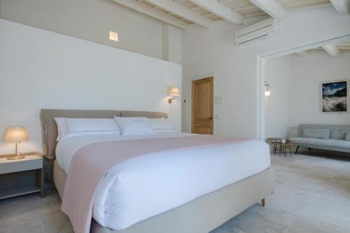 a white bedroom with a large bed and a couch at Samarés in Ciutadella