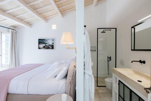 a white bedroom with a bed and a bathroom at Samarés in Ciutadella