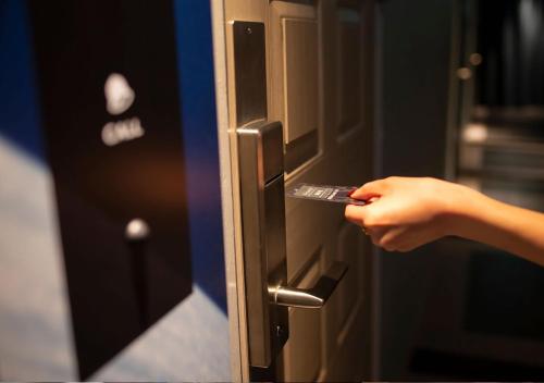 a person opening a door with their hand on it at HOTEL U's 香櫨園 in Nishinomiya