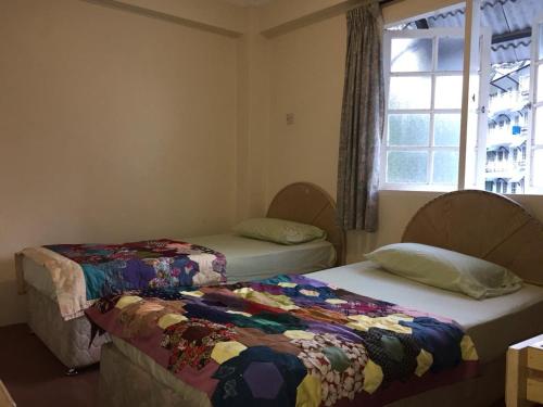 two beds sitting in a room with a window at Homstay Desa Anthurium in Tanah Rata