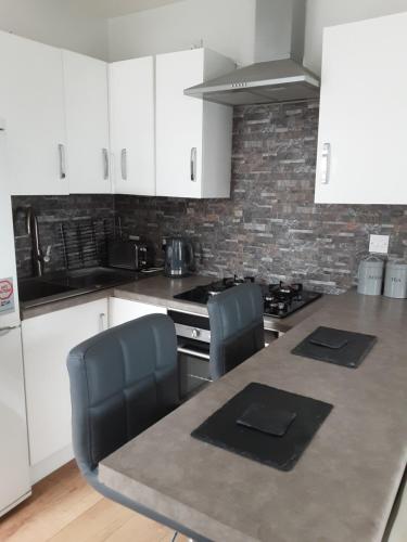 een keuken met witte kasten en een tafel met stoelen bij Esplanade Seaside View Apartment in Porthcawl