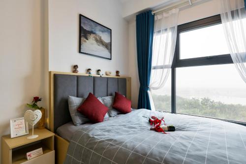Schlafzimmer mit einem Bett mit roten Kissen und einem Fenster in der Unterkunft THOC ECOPARK Blue home -0916 with Golf course View in HÆ°ng YÃªn