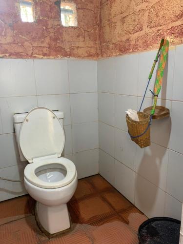 a bathroom with a toilet and a basket on the wall at Bamboo Forest River View Hostel in Ywama