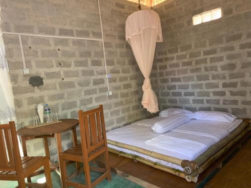 a bed in a room with a table and chairs at Bamboo Forest River View Hostel in Ywama