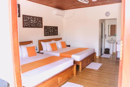 two beds in a room with wooden floors at ANB Surf View in Tangalle