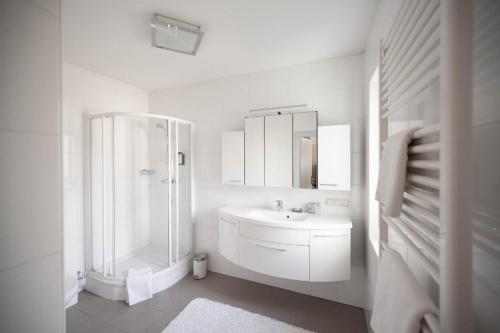 a white bathroom with a shower and a sink at Aparthome L.I.N.Z. in Bergham