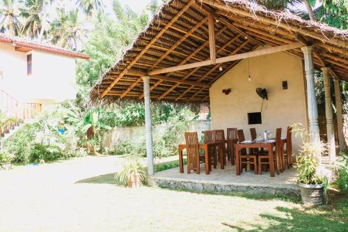 a patio with a table and chairs under a pergola at ANB Surf View in Tangalle