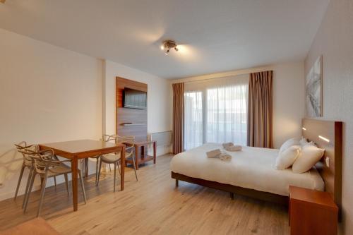 Cette chambre comprend un lit, une table et un bureau. dans l'établissement Résidence Azurea, à Aix-les-Bains