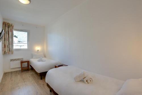 a white room with two beds and a window at Résidence Azurea in Aix-les-Bains
