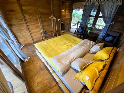 a large bed in a room with yellow sheets and pillows at Pu Luong Ecocharm in Hương Bá Thước