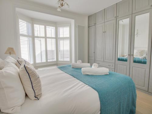 a large white bed with two towels on top of it at Seahorse Cottage in Weymouth