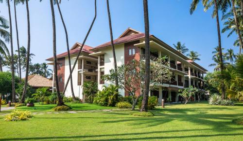 a house with palm trees in front of it at Eskala Hotels and Resorts in Ngwesaung