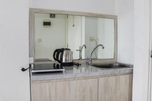 a kitchen with a sink and a microwave at Minimalist Studio Apartment at Poris 88 with City View By Travelio in Tangerang