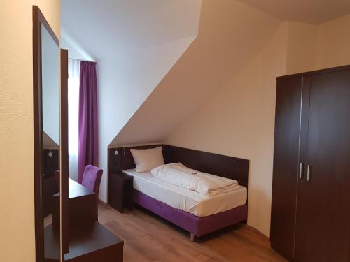 ein kleines Schlafzimmer mit einem Bett und einem lila Schrank in der Unterkunft ates Hotel Lampertheim in Lampertheim