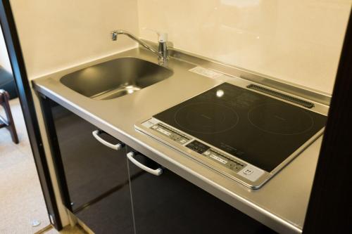 a kitchen counter with a sink and a tablet on it at Guest House One More Heart Kyoto Station South 4 in Kyoto