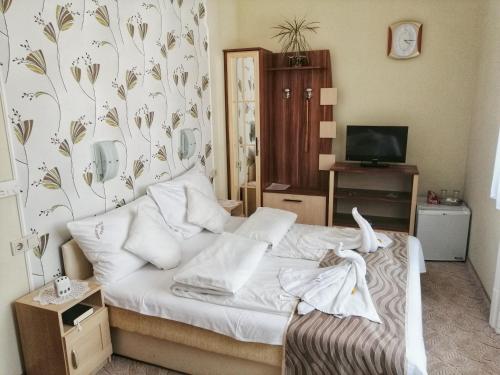 a bedroom with a bed with white sheets and a floral wallpaper at Szent István Wellness Panzió in Makó