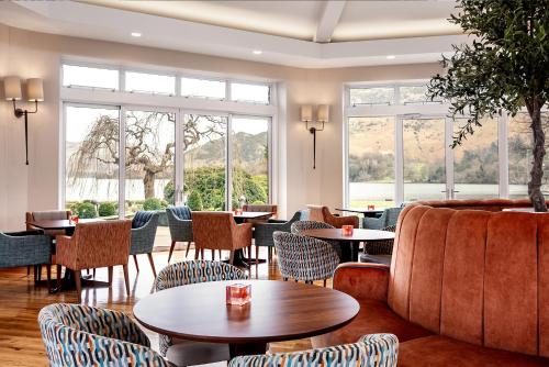 un restaurante con mesas, sillas y ventanas en The Inn On The Lake en Glenridding