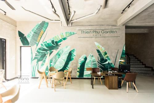 a room with chairs and a wall with a mural of leaves at Thien Phu Garden Hotel in Hanoi
