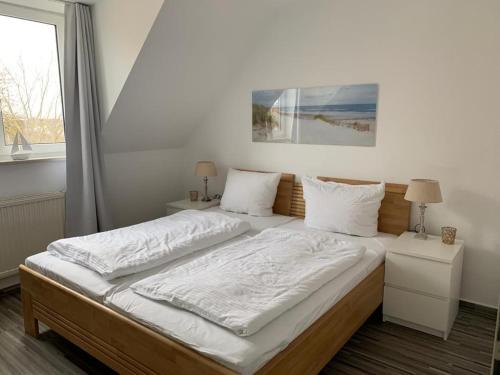 Schlafzimmer mit einem Bett mit weißer Bettwäsche und einem Fenster in der Unterkunft Appartementhaus Ulmenhof in Kühlungsborn