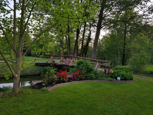 Ferienwohnung Wasserlilie في Kolonie: جسر فوق نهر به ورد وحديقة