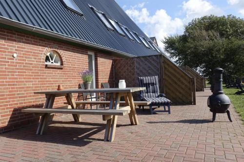 a picnic table and two chairs on a brick patio at Ferienhof Land-Idyll in Osterhever