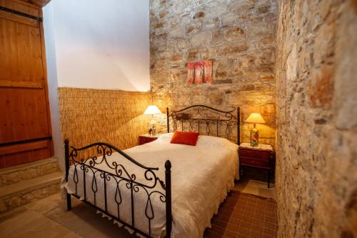 a bedroom with a bed and a stone wall at Constantias stone houses in Lofou