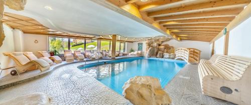een binnenzwembad met stoelen en een poolhouse bij Dolomitenhotel Weisslahnbad in Tires