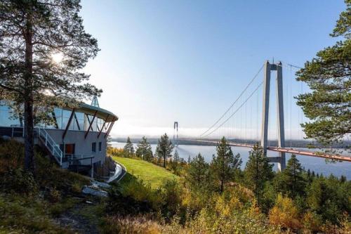 a bridge over a river with a building on a hill at Hotell Höga Kusten in Sandöverken