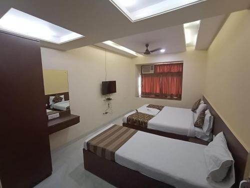 een slaapkamer met 2 bedden en een televisie. bij Lucky Service Apartments in Mumbai