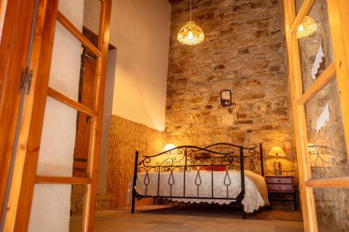 a bedroom with a iron bed in a brick wall at Constantias stone houses in Lofou