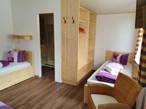 a small room with two beds and a chair at Pension INGE in Hinterstoder