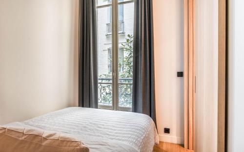 a bedroom with a bed in front of a window at Comfy 1BR apartment Montaigne Champs-Elysées in Paris