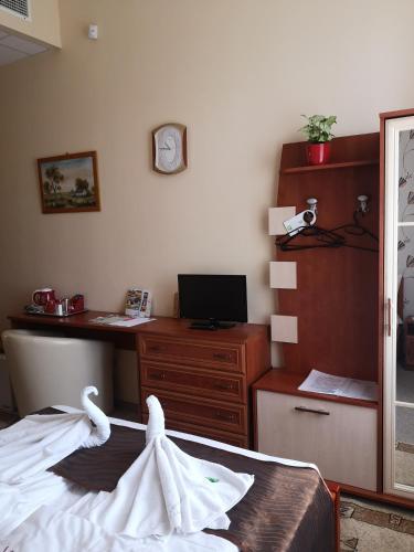 a bedroom with a bed and a desk with a computer at Szent István Wellness Panzió in Makó