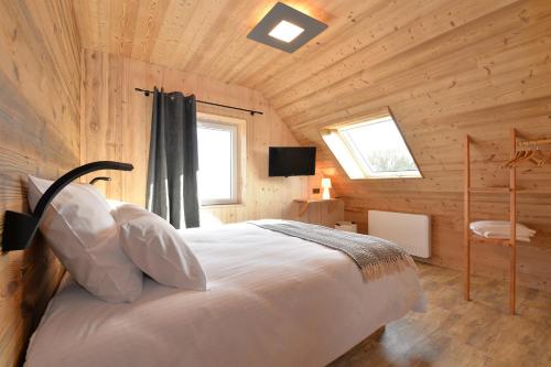 um quarto com uma cama num chalé de madeira em Le Clos Ô Daims em Widensolen