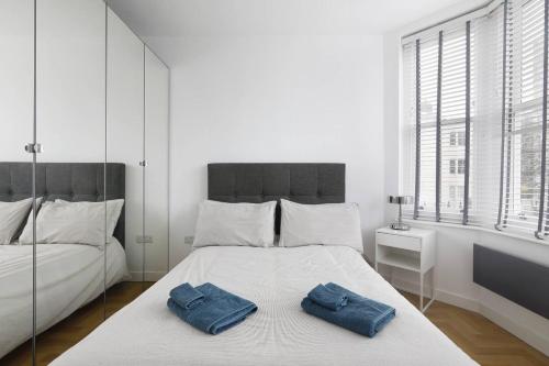 a white bedroom with two blue towels on a bed at Clarence Square in Brighton & Hove